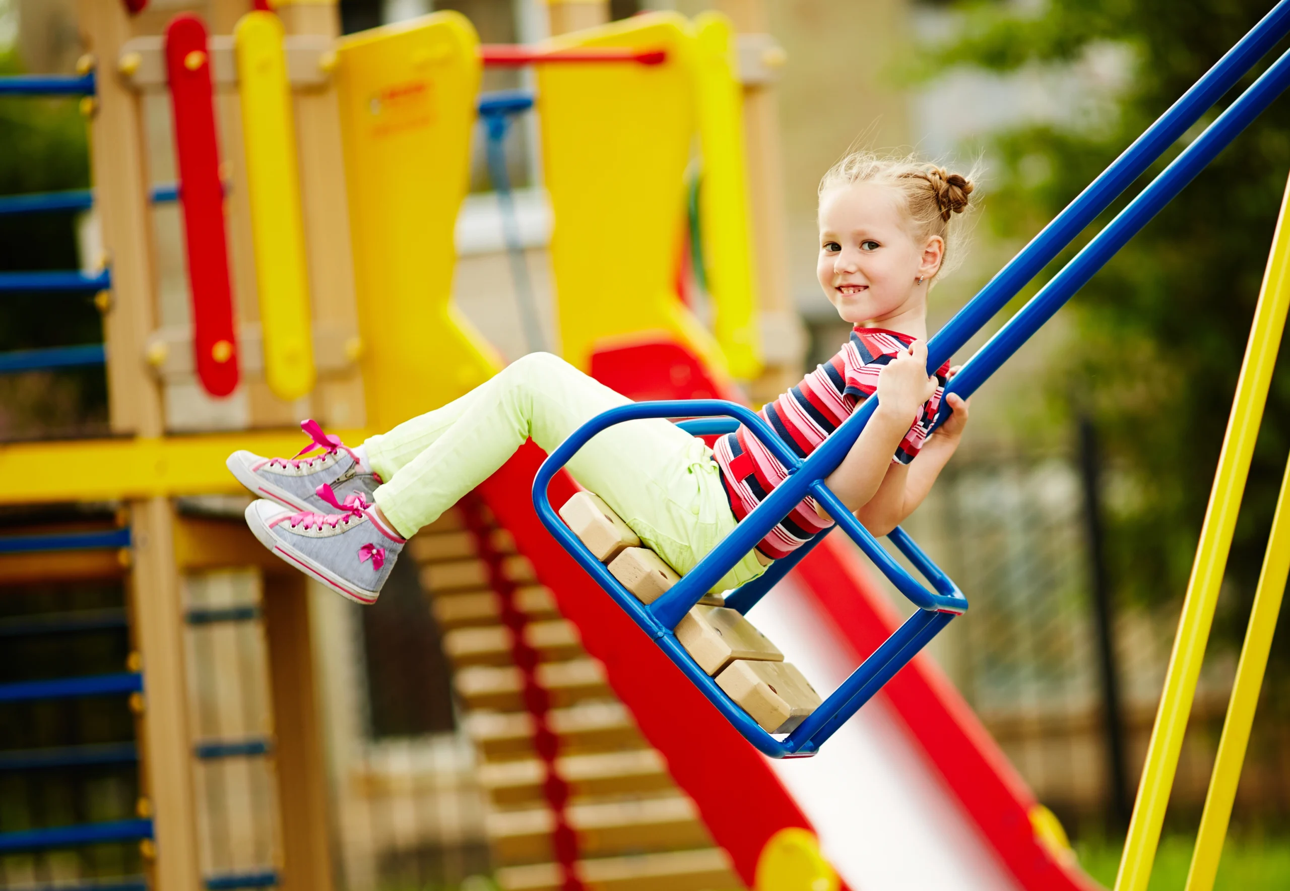 Niña sonriente en un columpio de un parque infantil